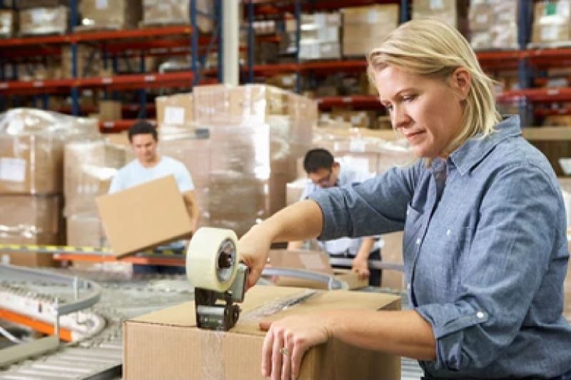 "Worker sealing packages in a warehouse, showcasing efficient 3PL services for inventory management, packing, and distribution."